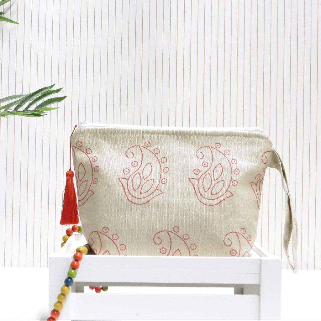 Beige pouch with red paisley patterns and tassel on a white surface with a light background